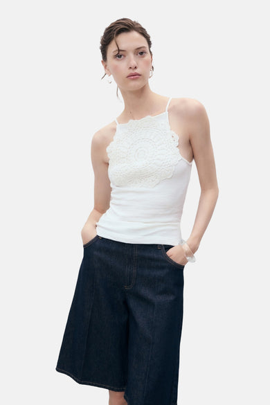 T-shirt blanc avec des bandes de spaghetti de MANGO, doté d'un détail crocheté sur la poitrine et associé à des culottes en denim.