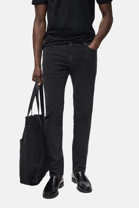 Jean slim fit gris anthracite de MANGO, avec une sacque noire et des chaussures en cuir noires.