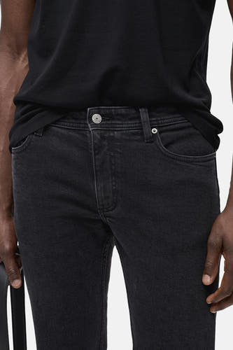 Jean slim fit couleur gris foncé de MANGO, avec fermeture à boutons et à glissière, associé à un T-shirt noir.