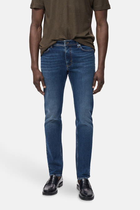 Jean slim de MANGO en denim bleu moyen, associé à un t-shirt marron et des loafers noirs.