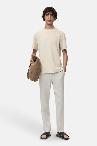 T-shirt gris à manches courtes de MANGO, porté avec un short léger et une sacoche marron.