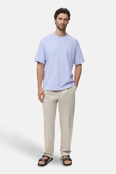 T-shirt bleu à manches courtes de MANGO, porté avec un pantalon beige et des sandales noires.