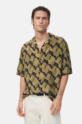 Chemise multicolore à manches courtes de MANGO, avec un motif abstrait et portée avec un pantalon blanc.
