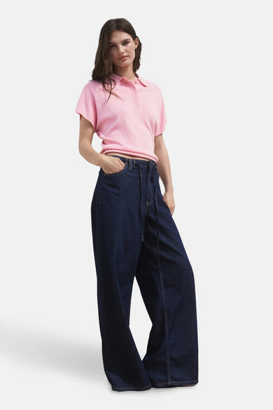 Polo rose à manches courtes de MANGO, porté avec des jeans bleus marine larges à taille élastiquée.