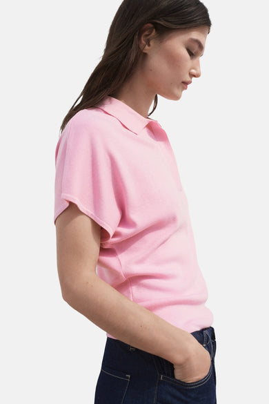 Polo rose à manches courtes de MANGO, porté avec un jean bleu foncé, vue latérale.