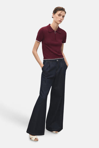 Veste Bordeaux avec col rond de MANGO, associée à des jeans foncés délavés et des chaussures ouvertes.