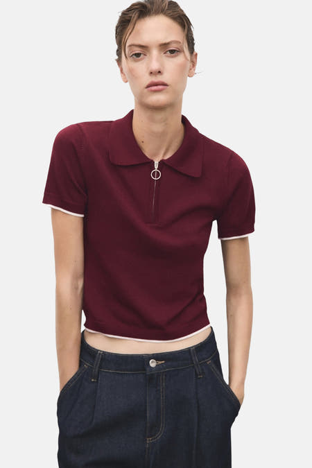 Veste Bordeaux avec col rond de MANGO, manches courtes et fermeture à glissière devant, associée à des jeans foncés.