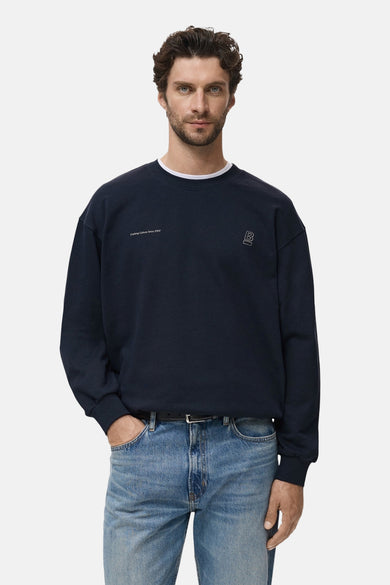 Pull-over bleu avec col rond de MANGO, doté de détails minimalistes et porté avec des jeans.