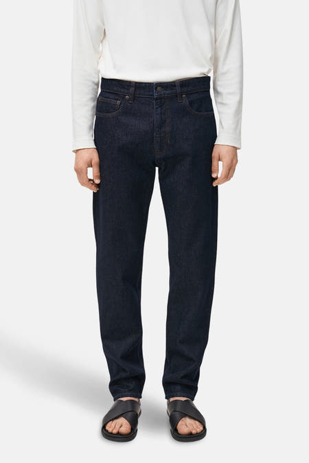 Jean bleu marine droit de MANGO, avec des poches classiques et porté avec un t-shirt blanc et des sandales noires.