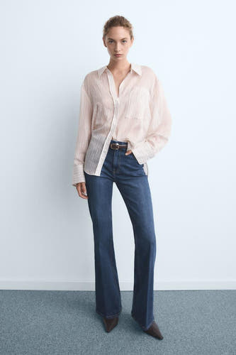 Jean bleu marine avec des jambes fuselées de MANGO, associé à une chemise rayée et un ceinture.