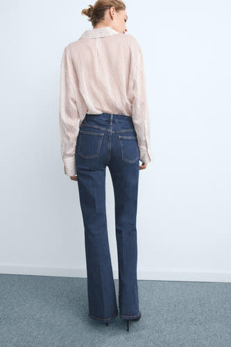Jean flare bleu marine de MANGO, avec un chemisier rayé et des talons hauts.