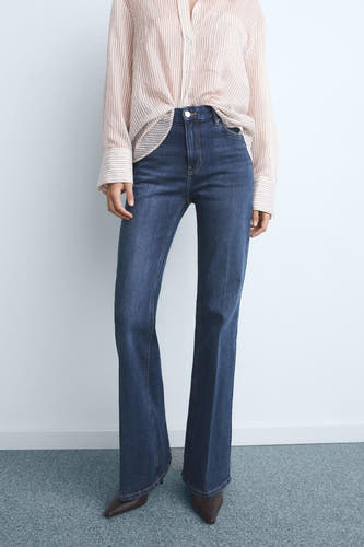 Jean flare bleu marine de MANGO, associé à une blouse rayée et des sandales brunes.