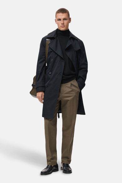 Gilet noir rond de cou M MANGOANGO port porté sous un trenchauau trench une pantalon kaki et des loafers.