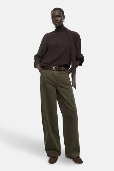 Khaki gekleurde jeans van MANGO, gedragen met een bruine riem, donkerbruine top en mocassins.
