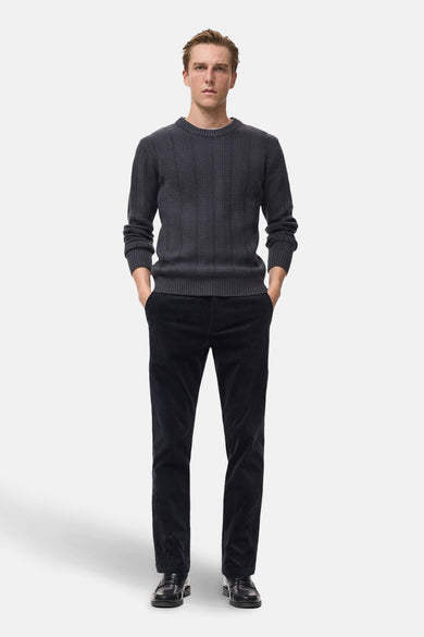Blauwe broek van MANGO, uitgevoerd in corduroy, gedragen met een grijze trui en zwarte schoenen.
