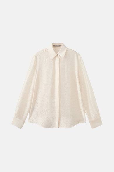 Chemise écru à manches longues de MANGO, avec des détails brillants et portée avec un pantalon beige.