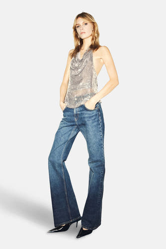 Zilverkleurige mouwloze blouse van MANGO, met een glinsterend uiterlijk en gecombineerd met jeans en zwarte schoenen.
