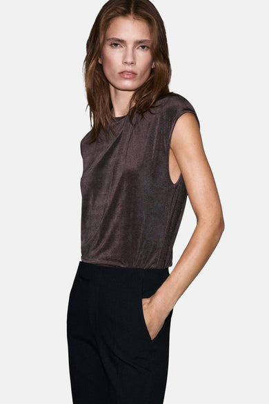 Blouse brune à manches courtes de MANGO, vue de derrière, associée à une jupe noire et un bracelet argenté.