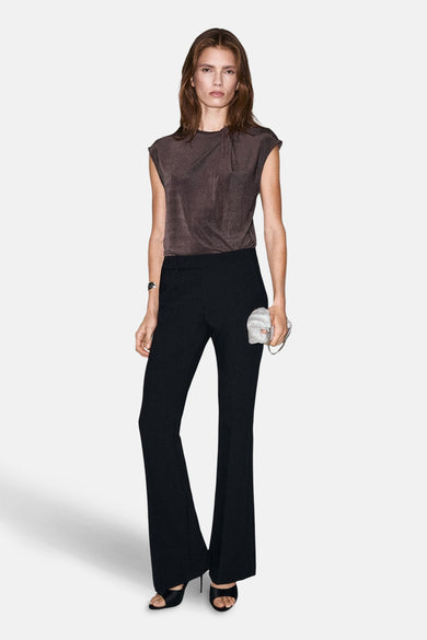 Bruine blouse met korte mouwen van MANGO, gedrapeerd detail op de voorkant, gecombineerd met zwarte flared broek.
