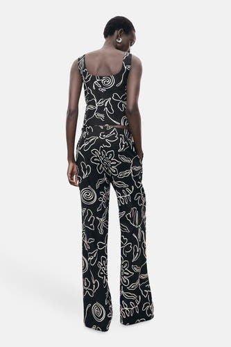 Pantalon noir de MANGO avec imprimé de fleurs blanches, vu de derrière.
