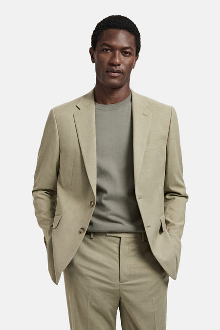 Blazer vert de MANGO, tailleur modèle avec collet revers et fermeture à boutons, combiné avec un pull et un pantalon verts.