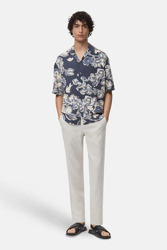 Chemise bleue à manches courtes de MANGO, portée avec une légère jupe et des sandales.