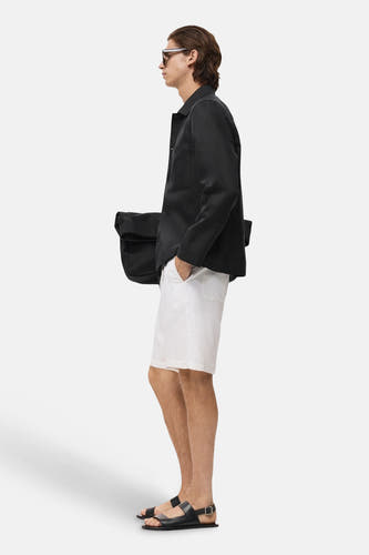 Veste courte noire de MANGO portée avec un short blanc et des sandales noires, vue arrière.