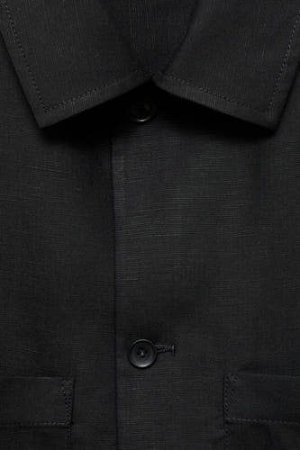 Manteau court noir de MANGO, avec un col, une fermeture à boutons et des poches discrètes.