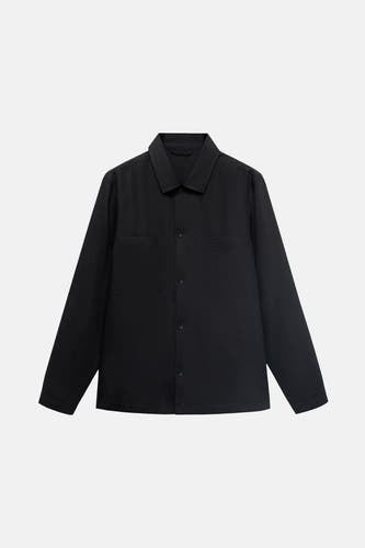 Manteau court noir de MANGO, avec des manches longues et des poches brodées, sur un léger fond.