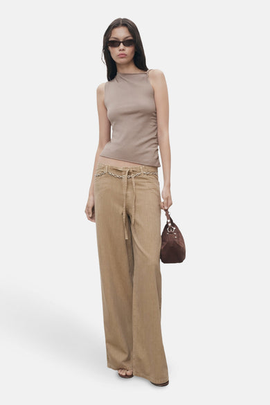 Jean beige MANGO avec une ceinture en chaîne, associé à un haut et une sac marron.