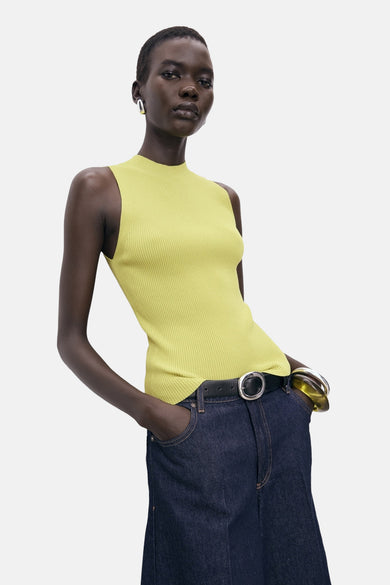 T-shirt jaune de MANGO, avec une texture rayée, porté avec une ceinture noire et un short en denim foncé.