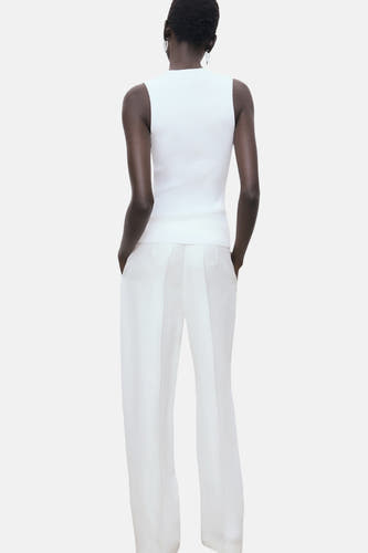 T-shirt blanc de MANGO, vu de l'arrière, associé à un short blanc et des boucles d'oreilles argentées.