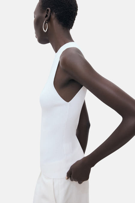 T-shirt blanc de MANGO, porté avec un pantalon blanc et des baskets noires.