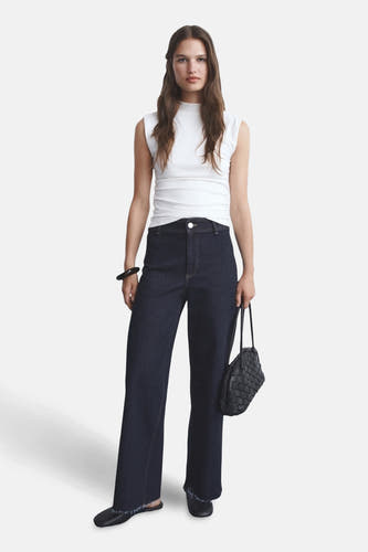 Jean bleu marine large de CATHERIN de MANGO, porté avec un haut blanc et une sacoche en cuir noir.