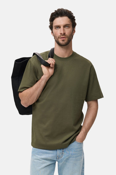 T-shirt kaki à manches courtes de MANGO, porté avec un sac noir et des jeans bleus.