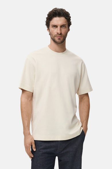 T-shirt beige à manches courtes de MANGO, porté avec un pantalon foncé.