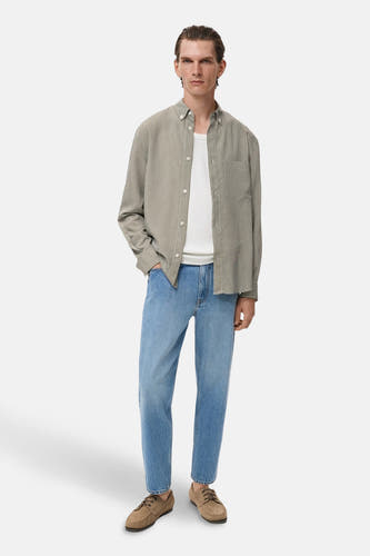 Chemise kaki à manches longues de MANGO, portée sur un T-shirt blanc et associée à des jeans bleus.