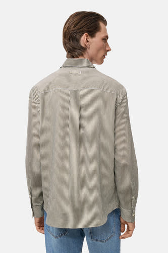 Chemise kaki à manches longues de MANGO, avec un motif à carreaux et une pliure sur le dos, portée avec un jean.