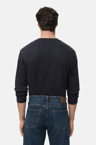 T-shirt noir à manches longues de MANGO, dos visible, associé à des jeans bleu marine et une ceinture marron.