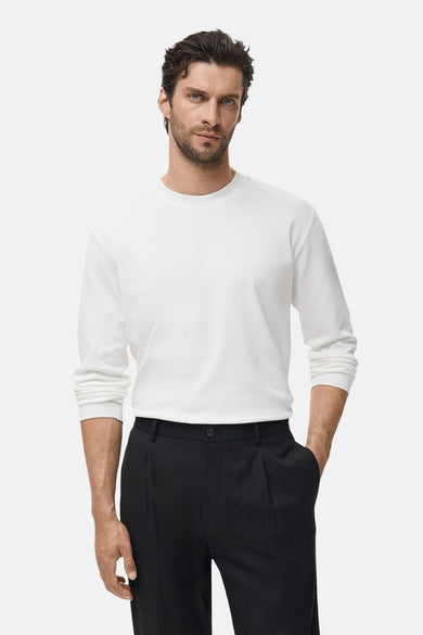 T-shirt blanc à manches longues de MANGO, associé à un pantalon noir.