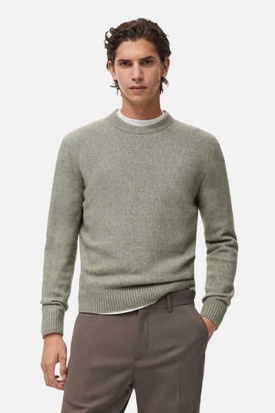 T-shirt vert avec col rond de MANGO, vu de l'arrière, porté avec un pantalon marron et un T-shirt blanc.