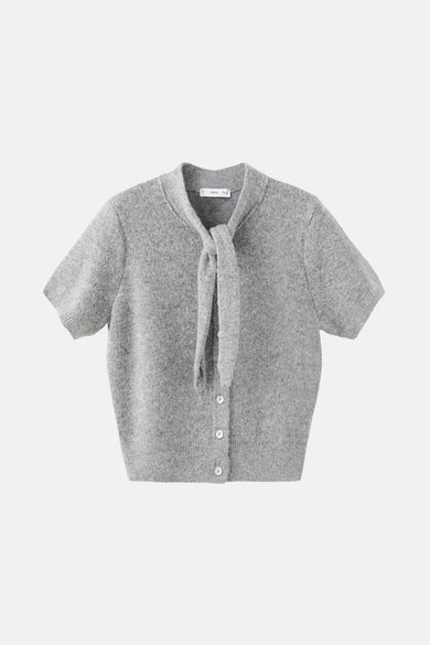 Gilet gris de MANGO, avec fermeture à boutons et collier lâche, associé à un pantalon marron et une veste.