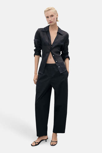 Pantalon noir de MANGO, avec des jambes larges et une ceinture élastique.