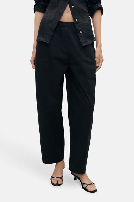 Pantalon noir de MANGO, avec des jambes larges et une ceinture élastique.