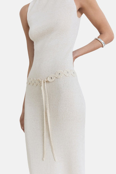 Robe beige sans manches de MANGO, avec une ceinture brodée et un bracelet argenté.