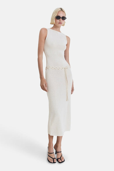 Robe beige sans manches de MANGO, avec une ceinture nouée et des sandales noires.