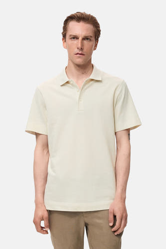 Polo écru à manches courtes de MANGO, avec une subtile texture et porté avec un pantalon kaki.