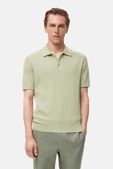 Polo vert de mantestes courtes MANGO, avec une fine texture à côtes, porté avec un pantalon vert.