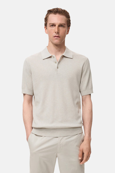 Polo écru à manches courtes de MANGO, en texture côtelée, porté avec un pantalon beige.