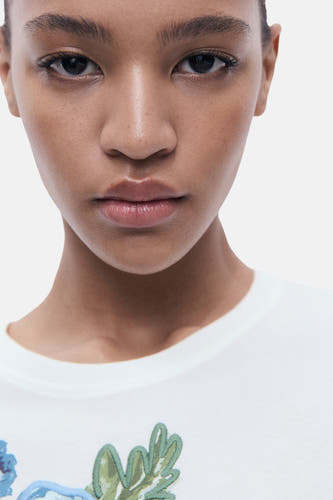 T-shirt multicolore (manches courtes) de MANGO, avec du travail de broderie floral sur un fond blanc.